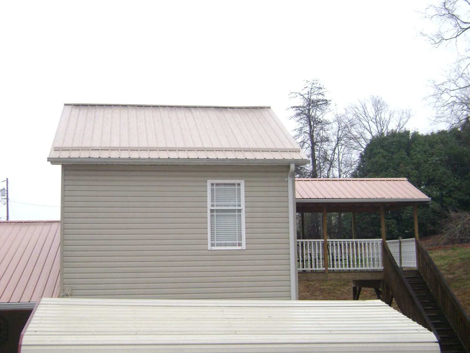 Tan metal roofs on a two story addition and attached porch, from a Roof Replacement job in Taylor